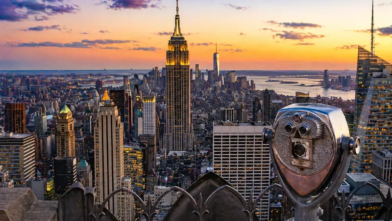 View of New York City skyline from Empire State Building observation deck at sunset with city lights and panoramic skyline