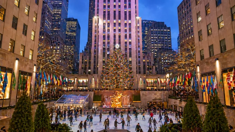 Rockefeller Center ice skating rink with Christmas tree and city lights in New York City at night