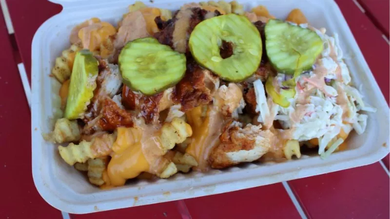 The Wick Celina Texas loaded fries with BBQ chicken, pickles, and creamy toppings street food style dish