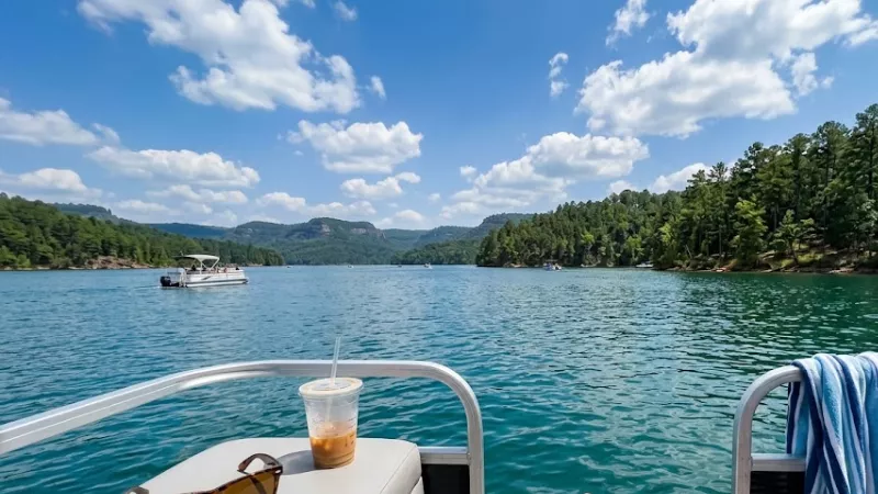 Pontoon boat rental on Broken Bow Lake near Hochatown Oklahoma during a July afternoon with pine-covered shoreline and Ouachita Mountains in the background