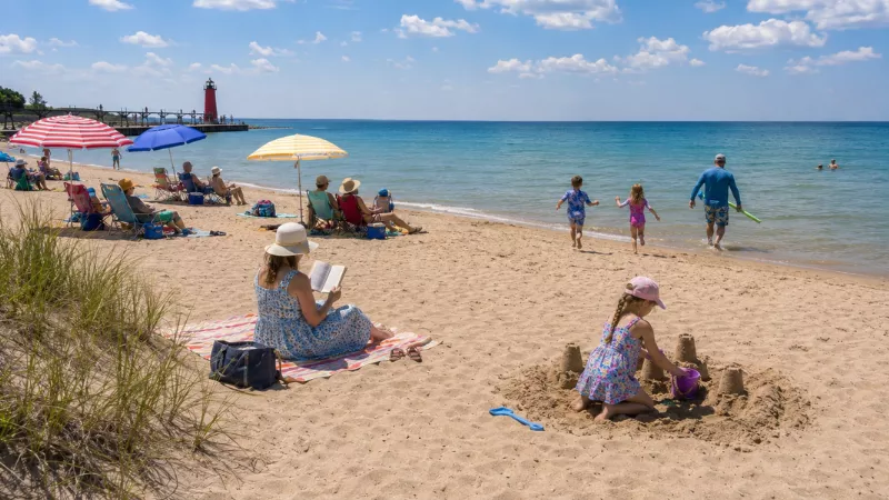 Families enjoying Charles Mears State Park beach with the channel and pier visible in Pentwater Michigan