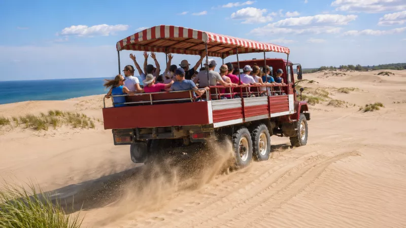 Mac Woods dune buggy riding over the Silver Lake Sand Dunes with passengers on a summer afternoon