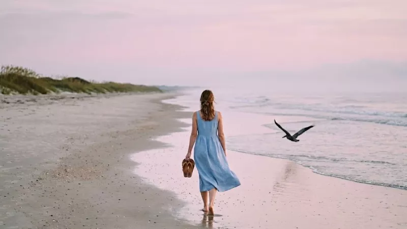 Solo traveler walking empty Huntington Beach State Park shoreline South Carolina near Pawleys Island at sunrise