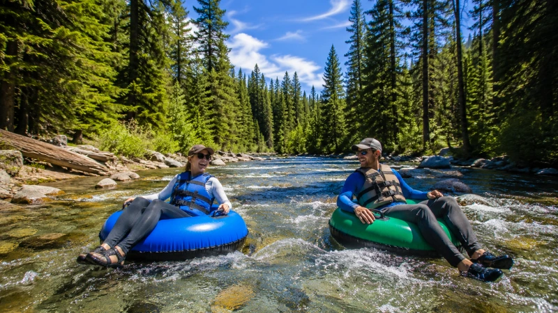 Two adults tubing down the Henry's Fork Snake River in Island Park Idaho on a sunny summer day