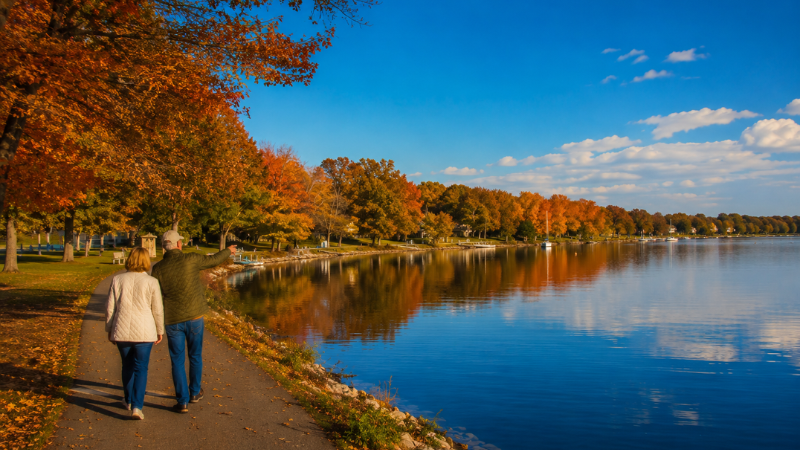 The Best Time to Visit Celina, Ohio 4 couple walking along Grand Lake St. Marys shoreline in Celina Ohio during fall with autumn foliage