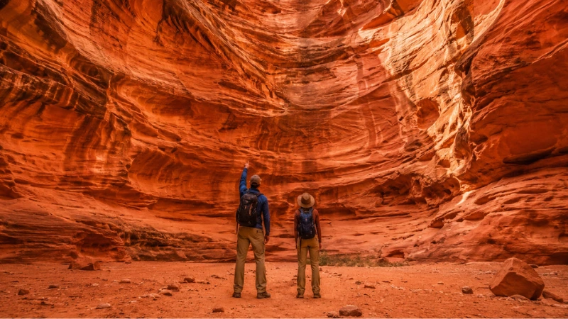 couple standing at the base of the Great Chamber sandstone amphitheater near Kanab Utah