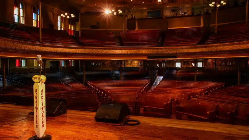 Inside Ryman Auditorium Nashville showing the original wooden church pews and warmly lit stage