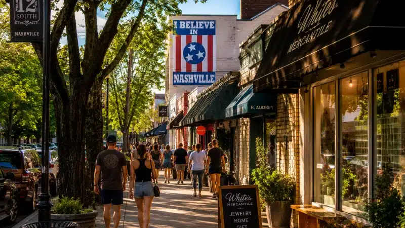 Tree-lined street in Nashville's 12 South neighborhood with boutique shops and pedestrians in afternoon light