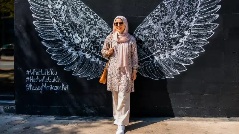 Woman posing in front of the famous white angel wings street mural in The Gulch neighborhood Nashville