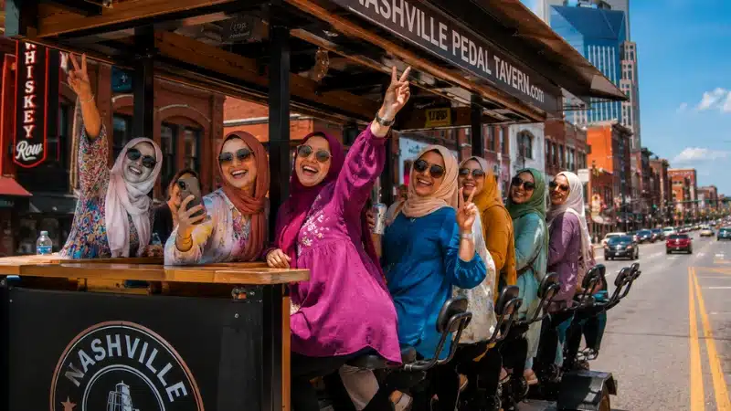 Group of women laughing and celebrating on a Nashville pedal tavern rolling through downtown streets